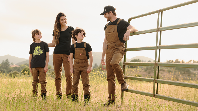 Family on a farm stands next to a cattle gate