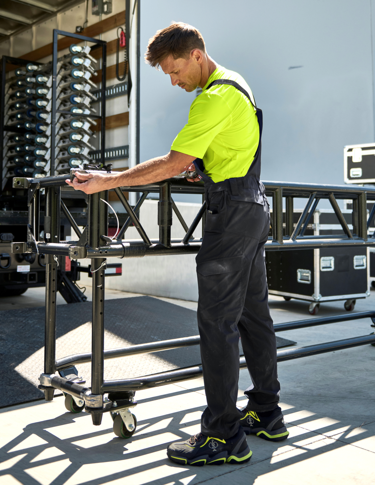 Person in high-visibility clothing working with a metal frame on a truck