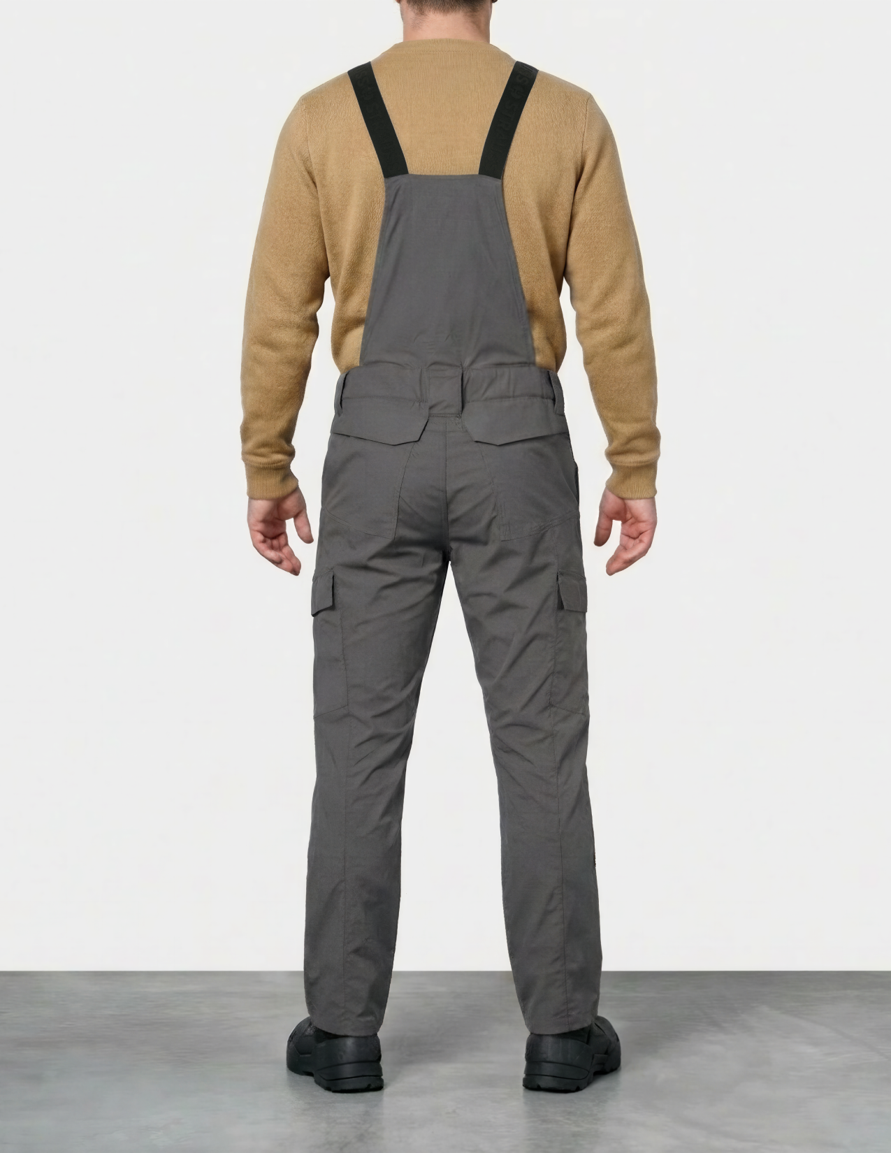 a man wearing gray bib overalls on a white background