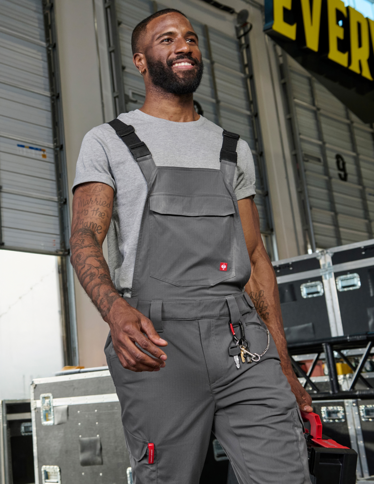 A man wearing gray cargo work bibs with a key attached to it