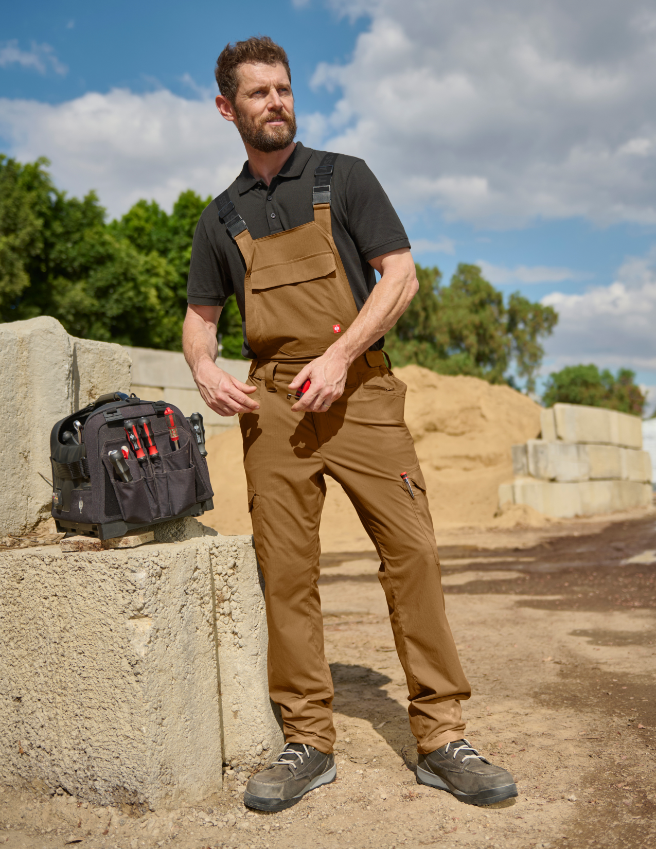A man wearing almondbrown cargo work bibs in a construction surrounding