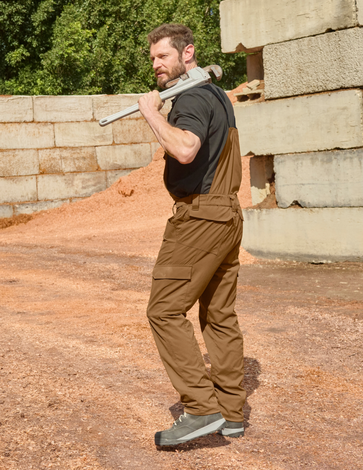 A man wearing almondbrown cargo work bibs and a metal pliers in his hand