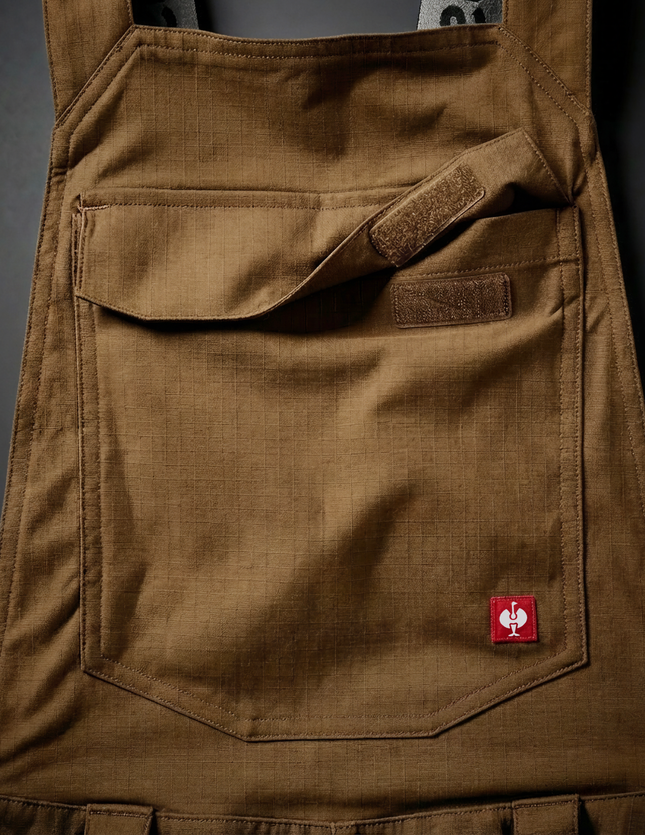 close-up of the front pocket of the bib with a red brand logo on it