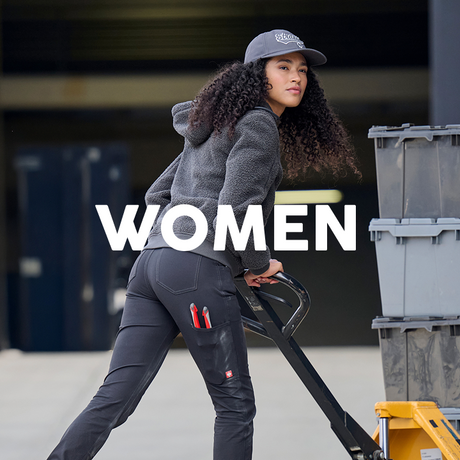 Woman pushing a cart with 'WOMEN' text overlay, wearing a cap and dark pants.