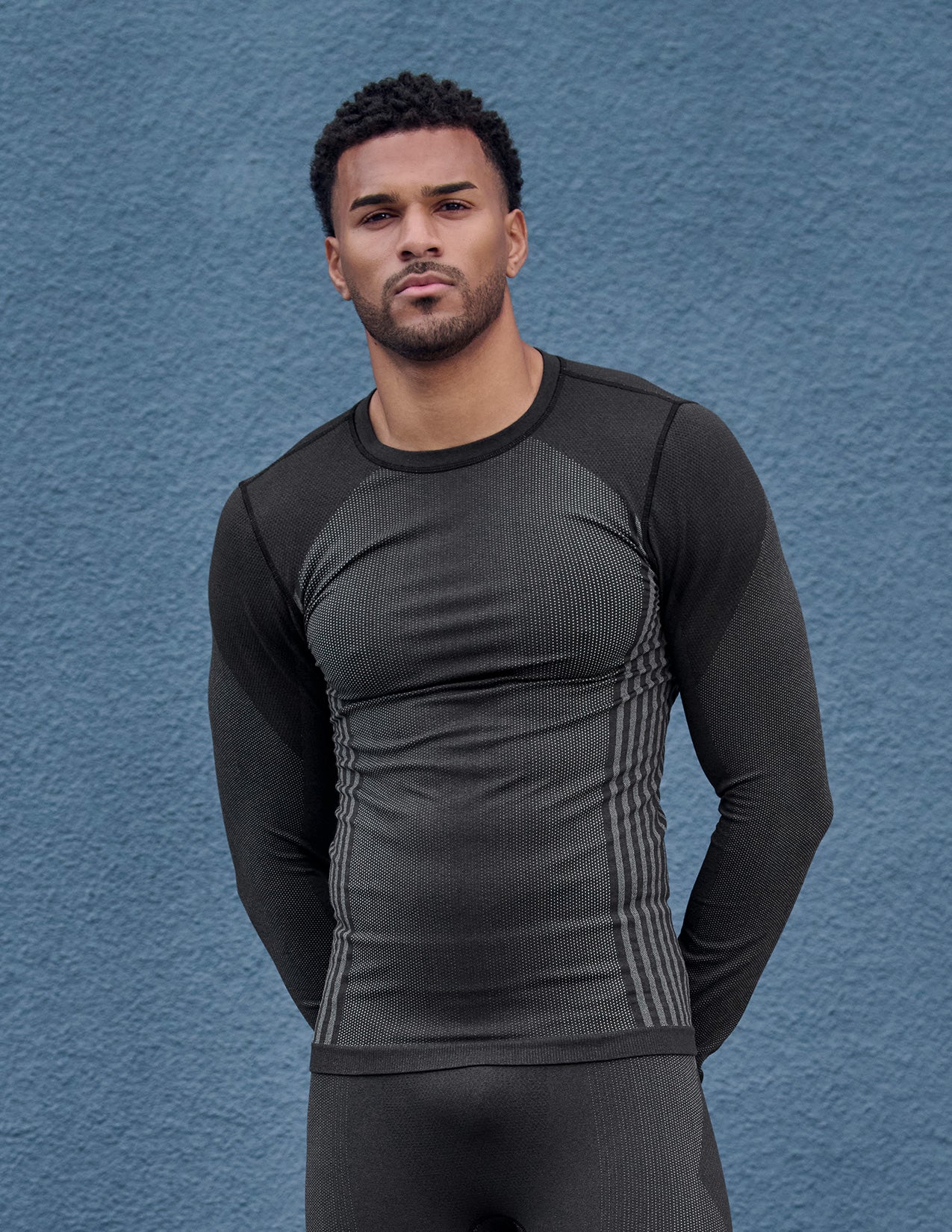 Man wearing a black long-sleeve thermal shirt against a blue background