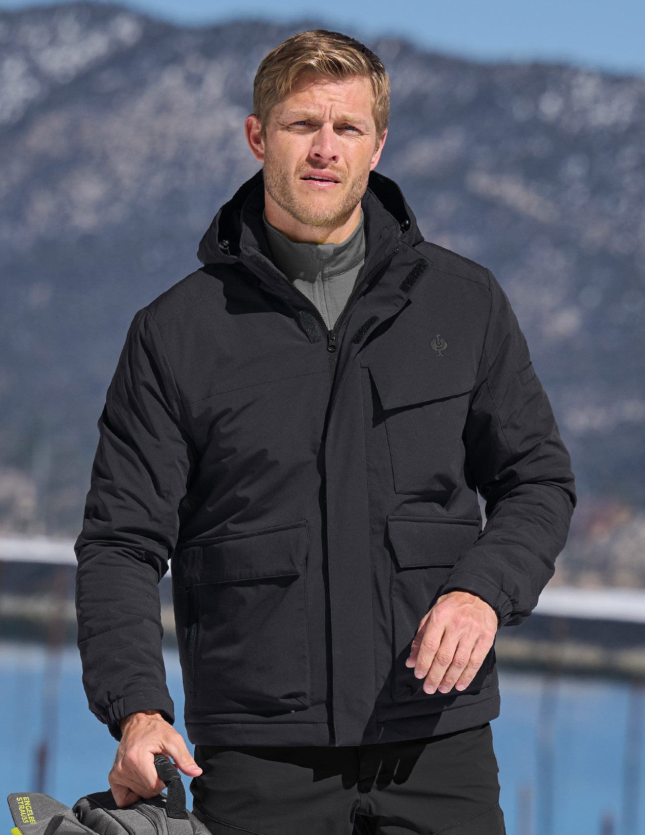 Man wearing a black jacket with mountains in the background