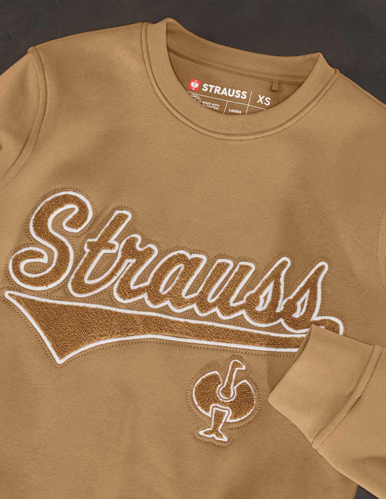 Brown sweatshirt with 'Strauss' branding on a dark background