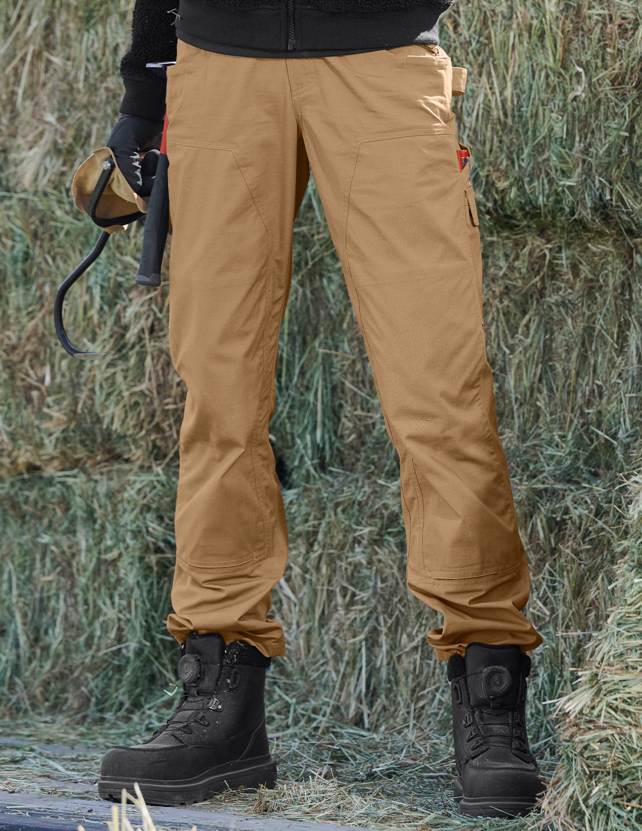 Person wearing tan pants and black boots standing in a grassy area