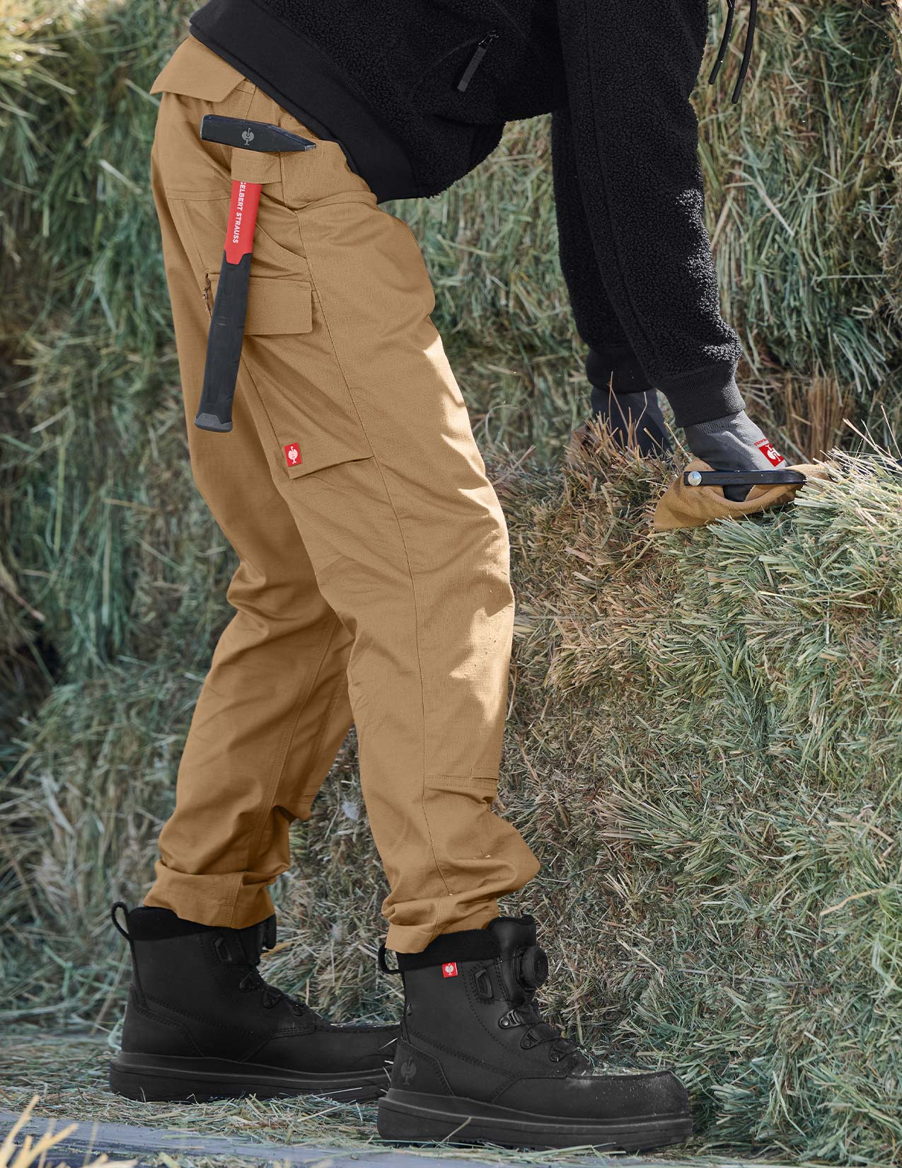 Person wearing tan cargo pants and black boots standing on a grassy field.