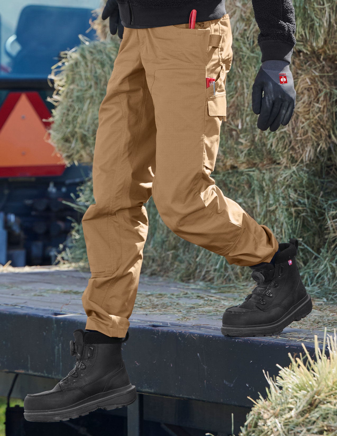 Person wearing tan work pants and black boots on a construction site.