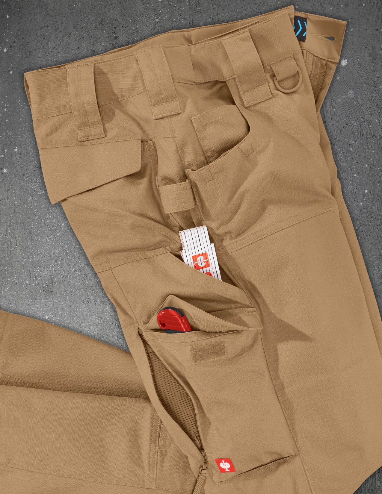 Brown tactical pants with multiple pockets on a gray surface