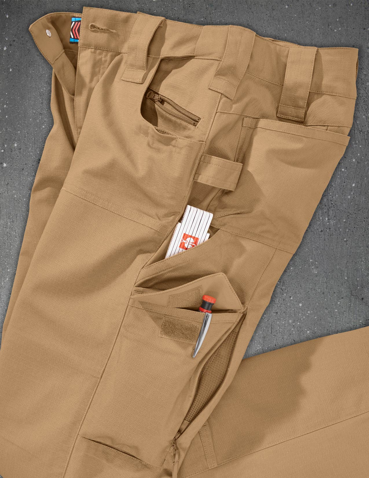 Brown cargo pants with multiple pockets on a gray surface