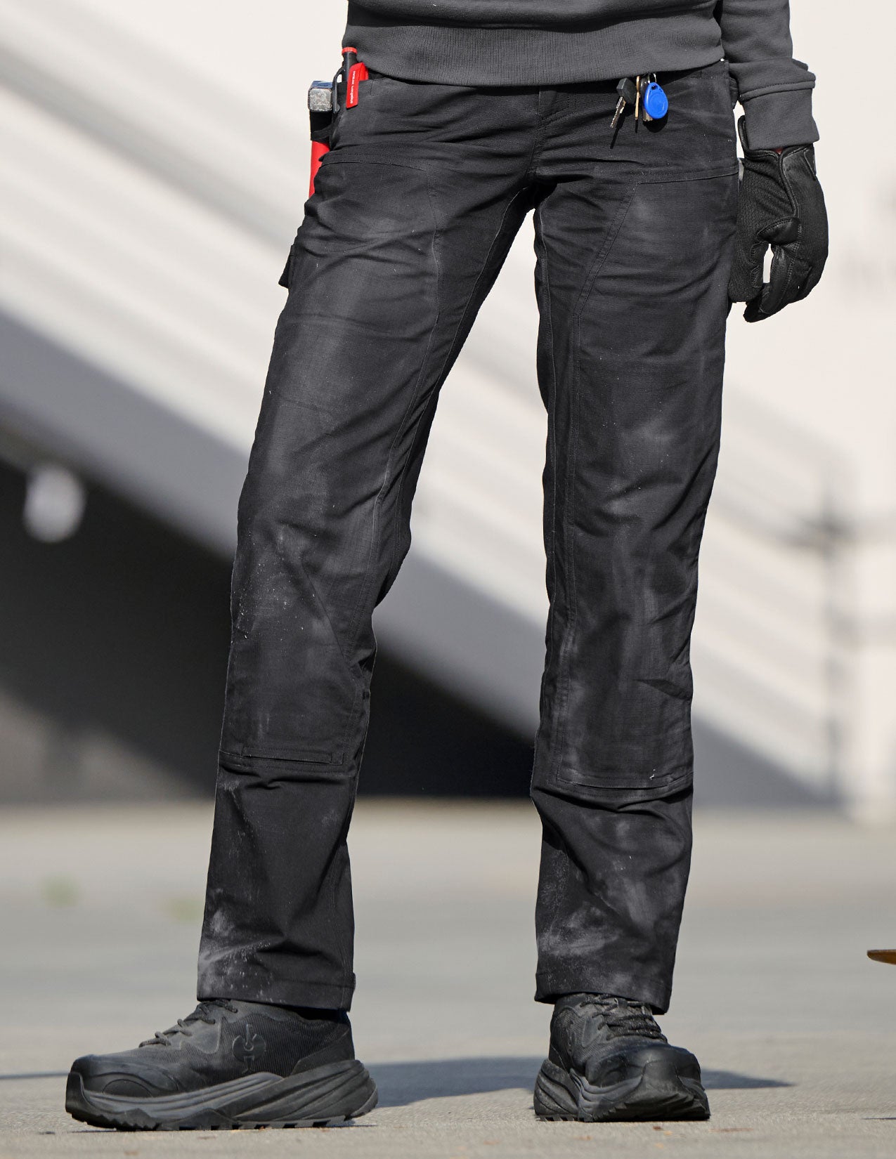 Person wearing black tactical pants with multiple pockets on a blurred background