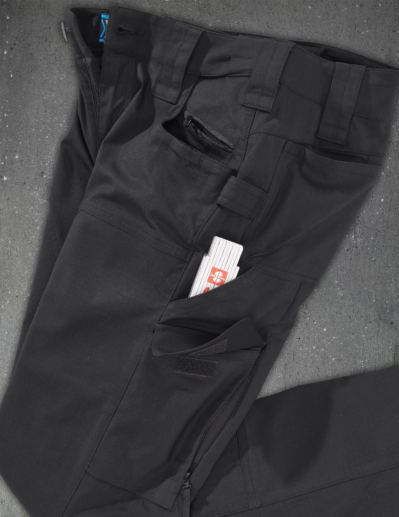 Black pants with a inch rule in the pocket on a gray surface