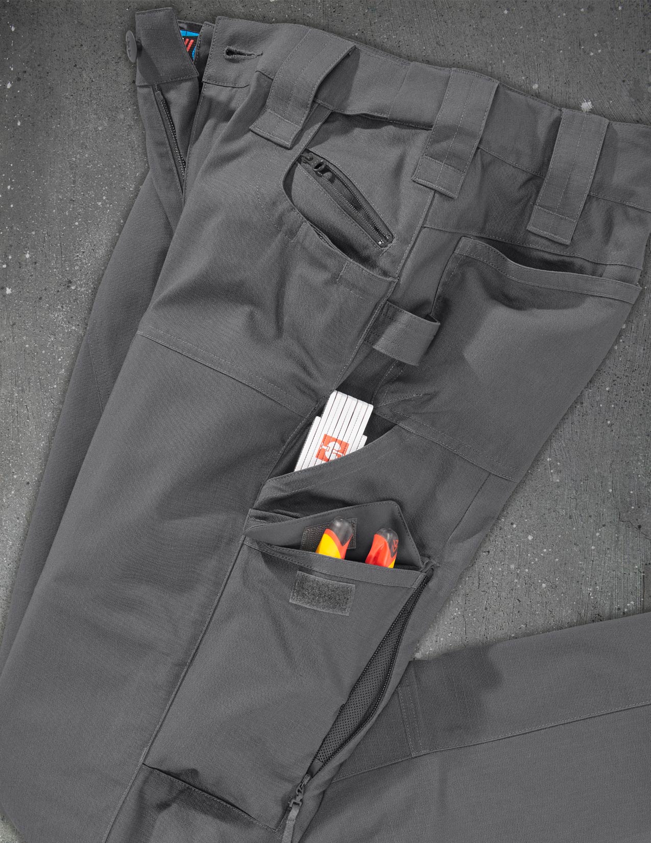 Gray tactical pants with multiple pockets on a gray surface