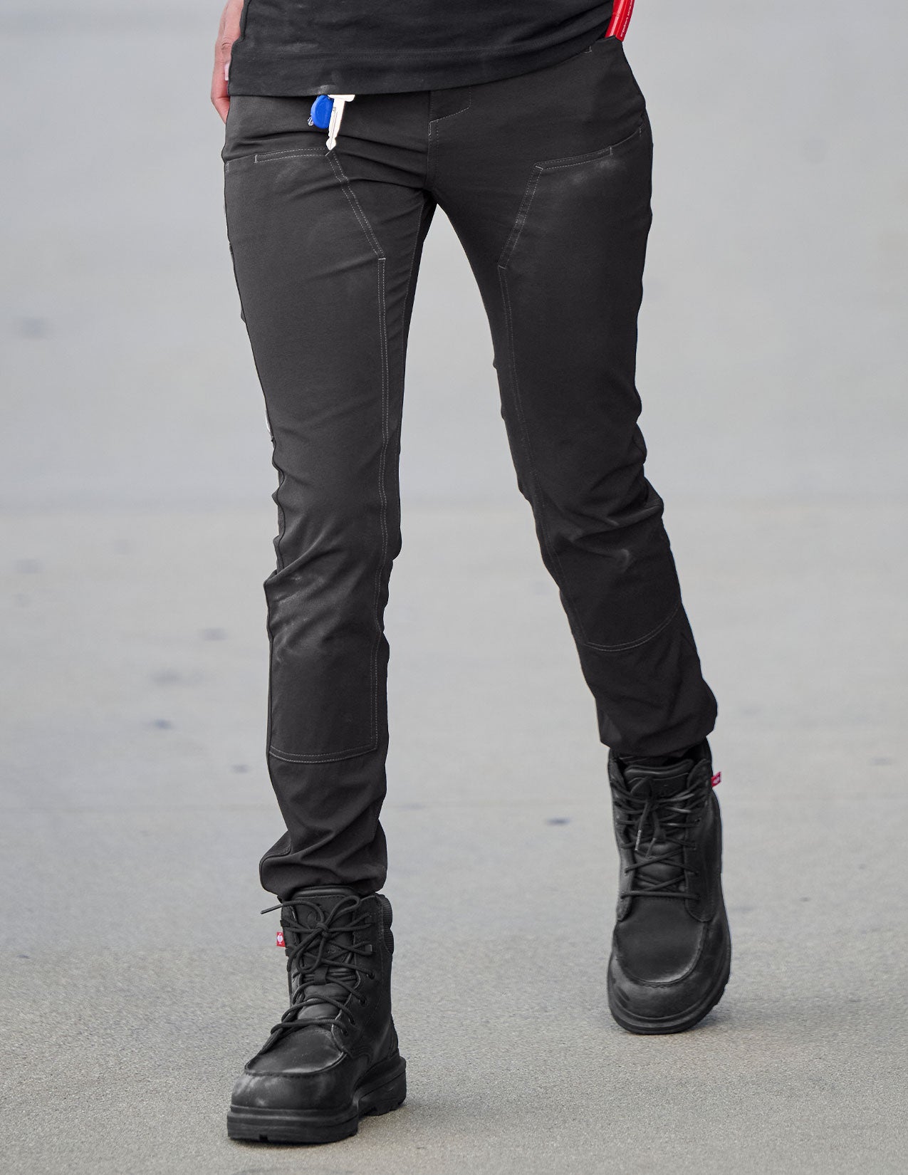 Person wearing black pants and black boots on a gray background