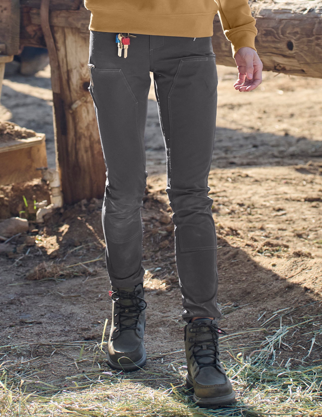 Person wearing dark gray pants and black boots in a rustic outdoor setting.