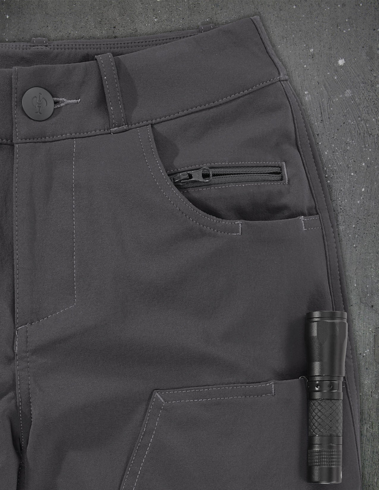 Close-up of dark gray pants with a flashlight in a pocket on a textured gray background