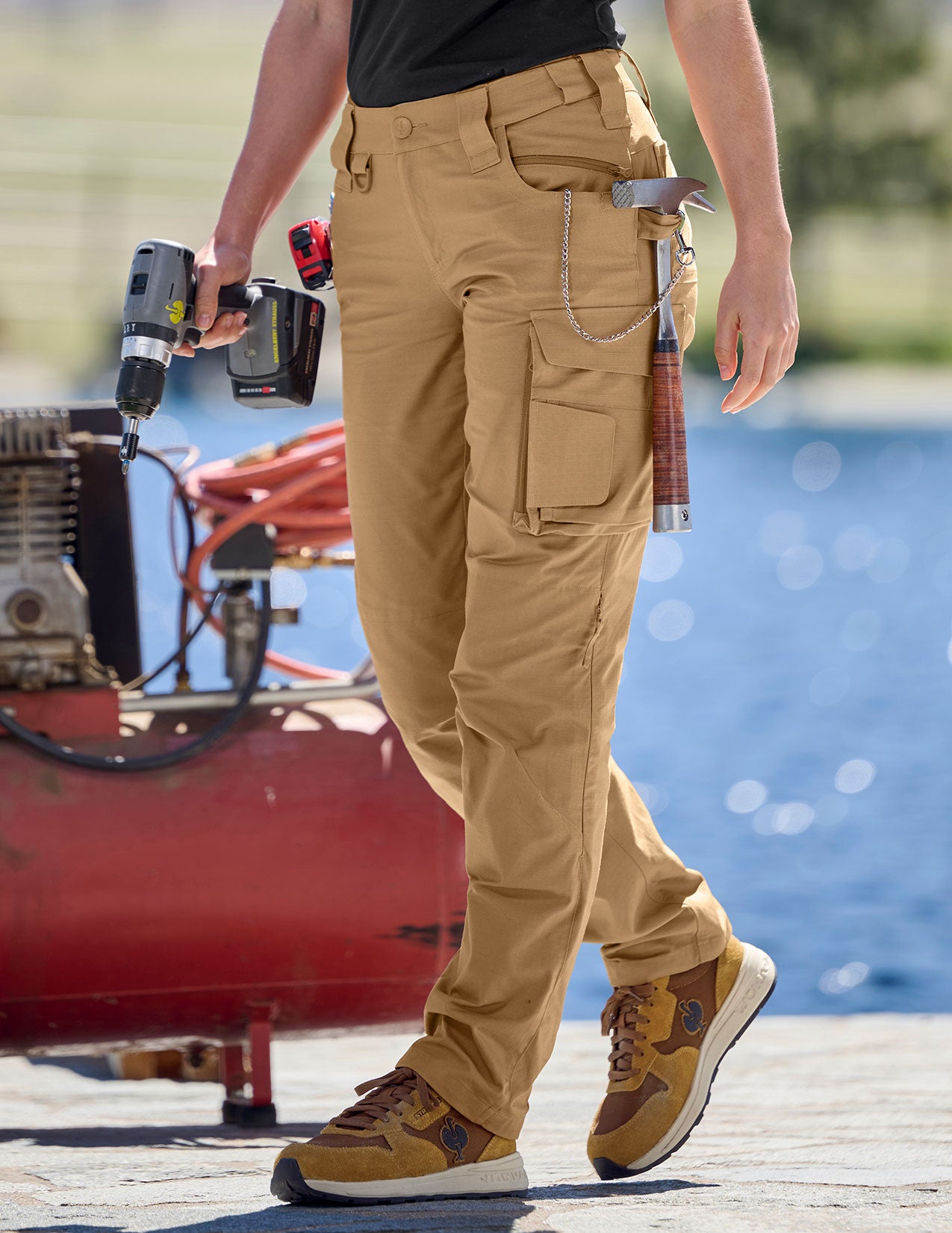 Person wearing tan work pants and shoes on a dock with tools in hand.