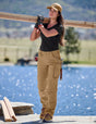 Person carrying wooden planks by a body of water