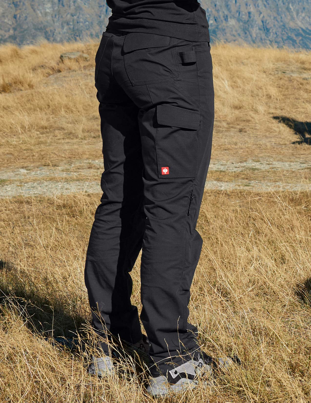 Person wearing black pants with a visible brand logo in a grassy outdoor setting