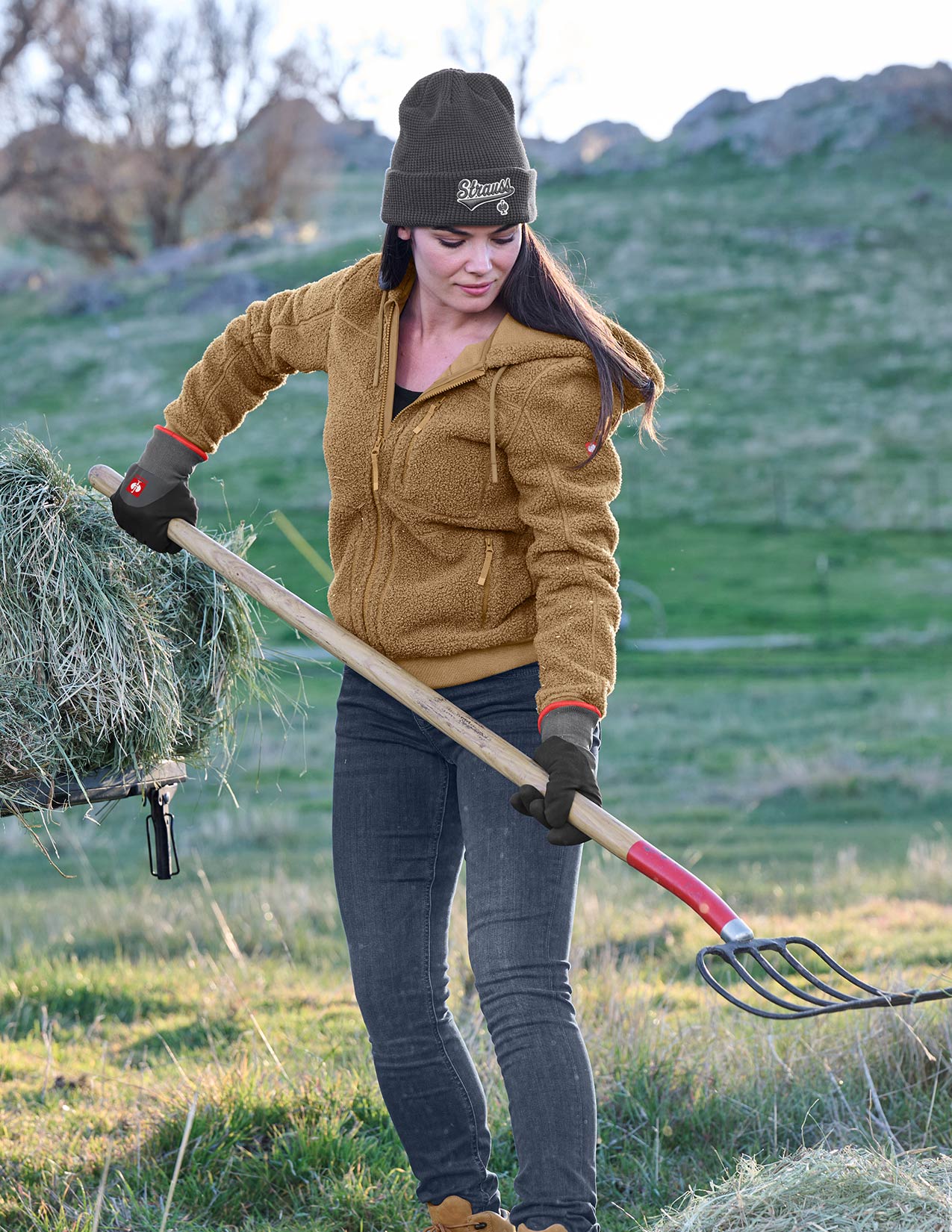 Women in a field using a pitchfork and carrying hay