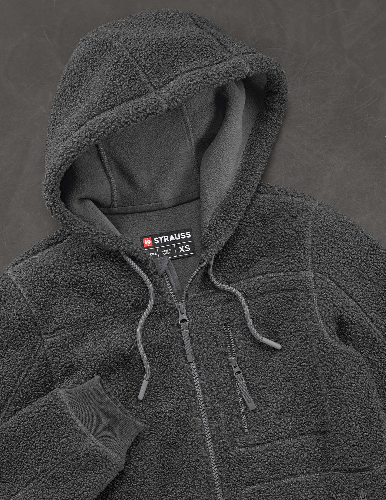 Dark gray fleece jacket with brand label on a dark background