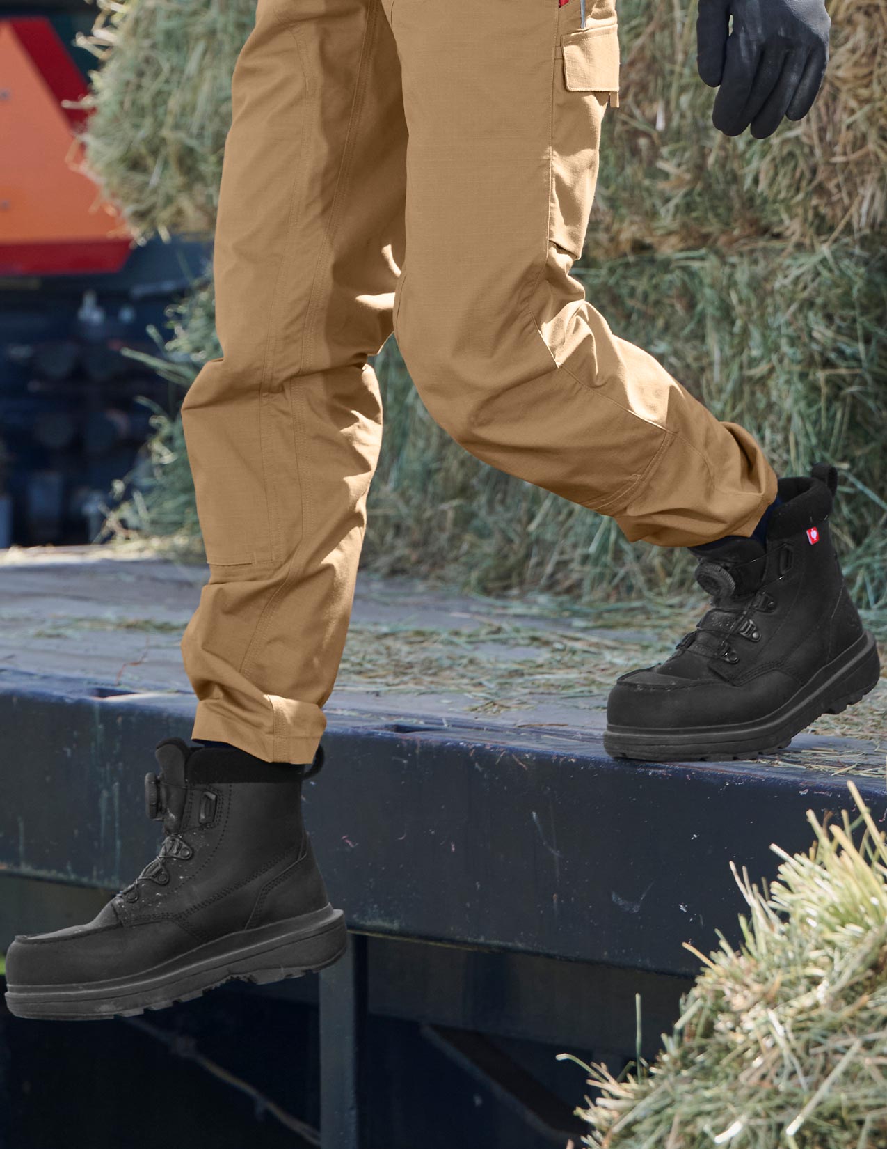 Person wearing black boots and beige pants standing on a platform with a blurred background
