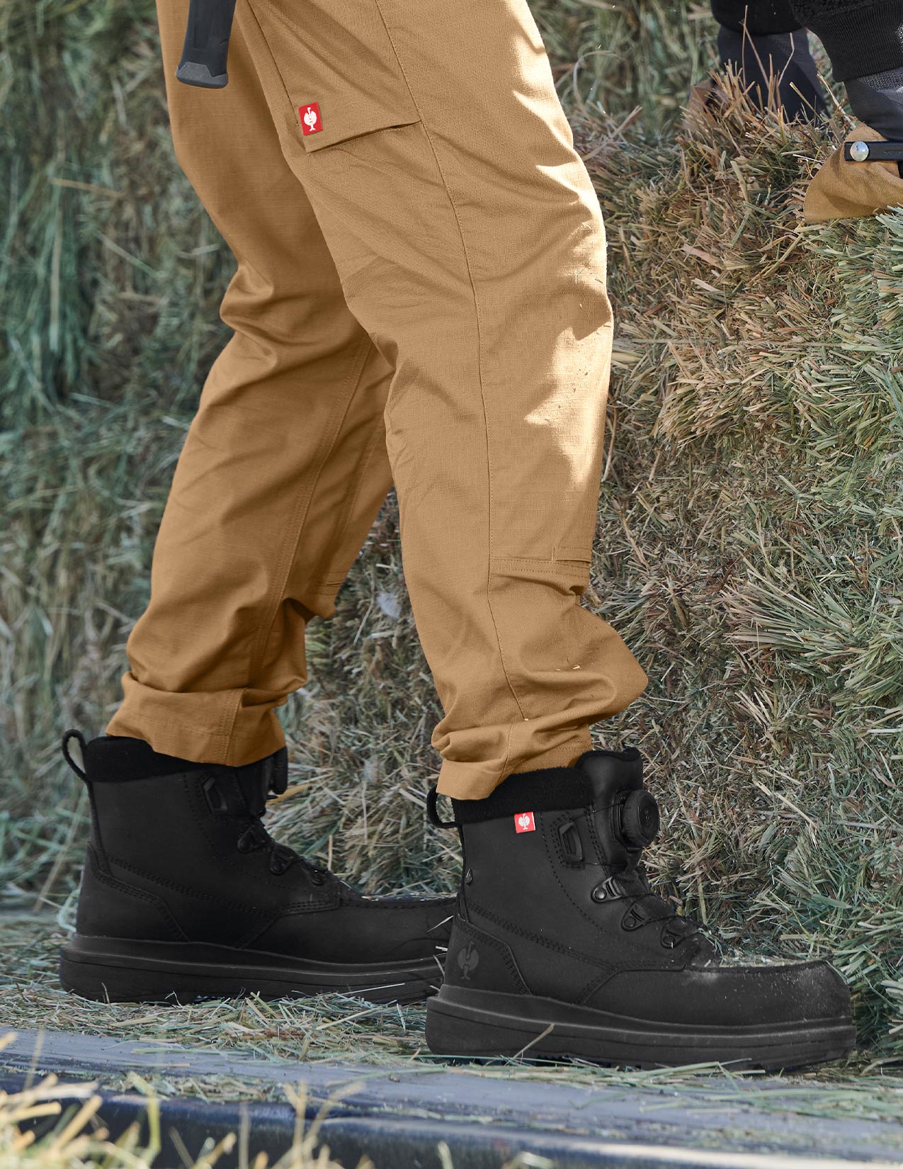 Person wearing brown pants and black boots standing on grass