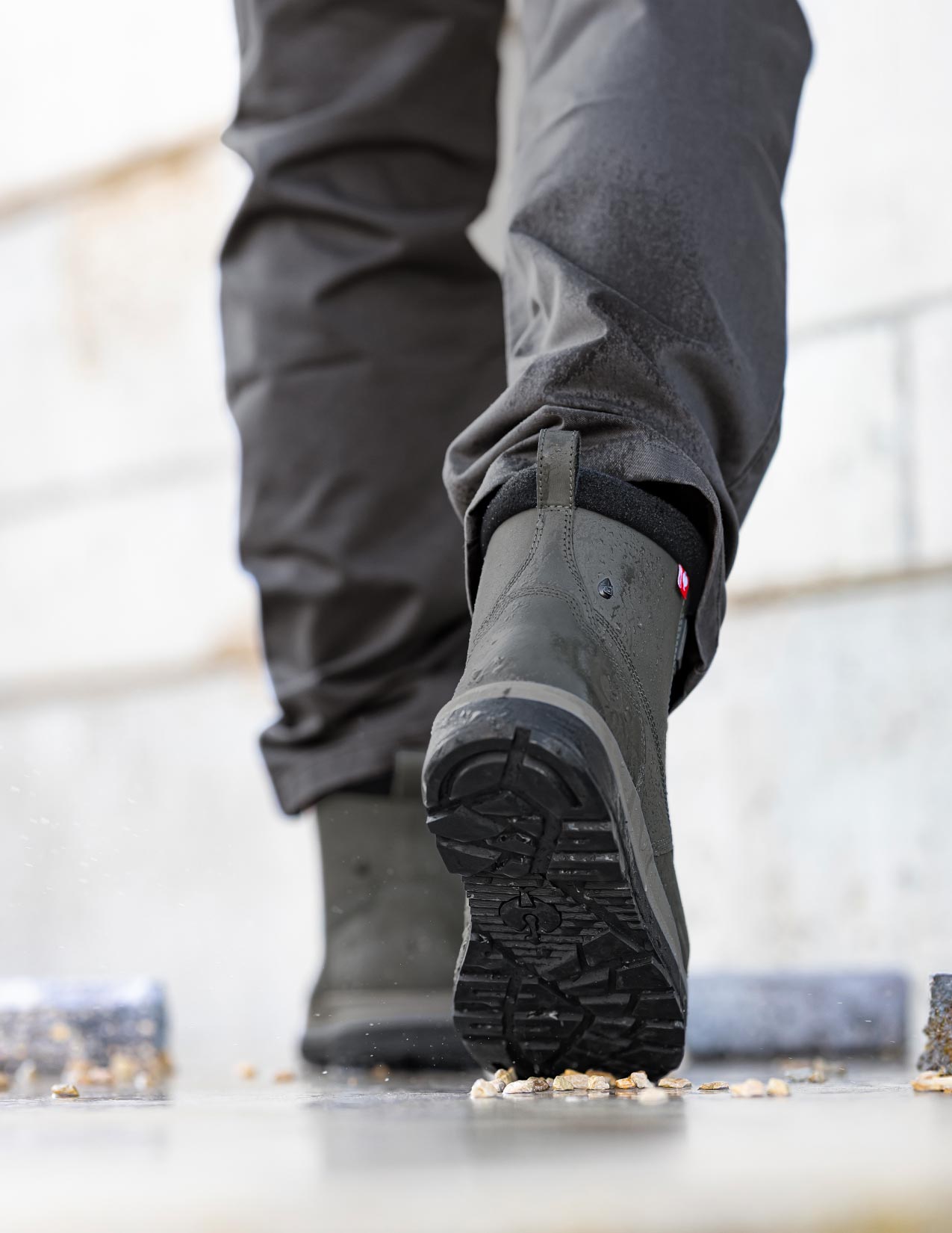 Person wearing carbongrey boots and pants on a light background