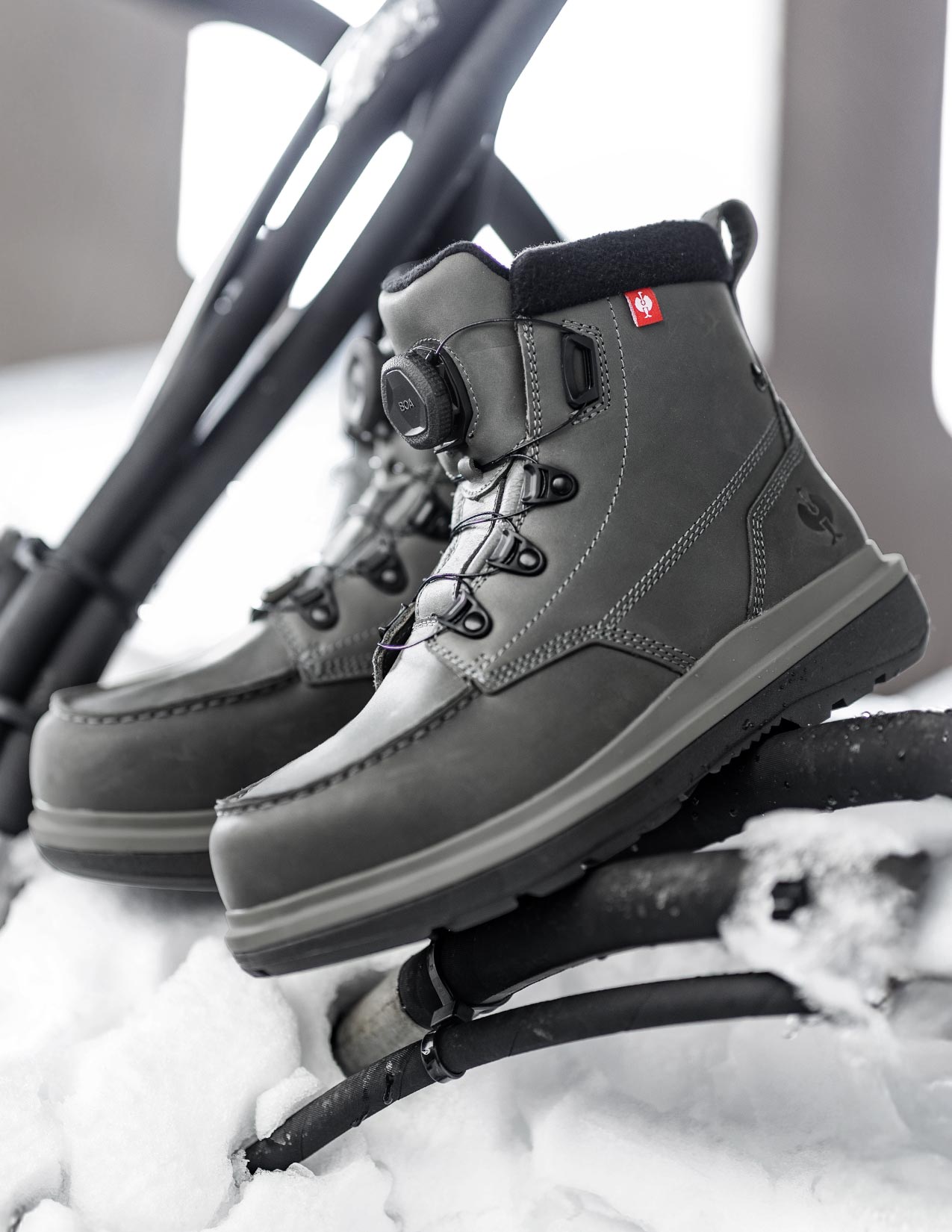 Carbongray winter boots with black soles on a snow-covered surface