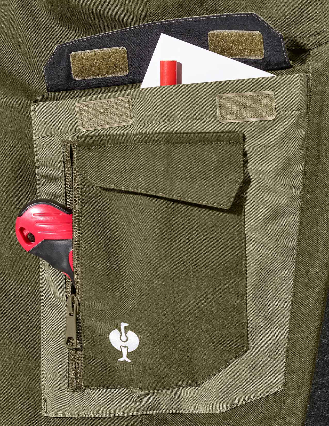 Close-up of a green pocket with tools and a logo on a green background