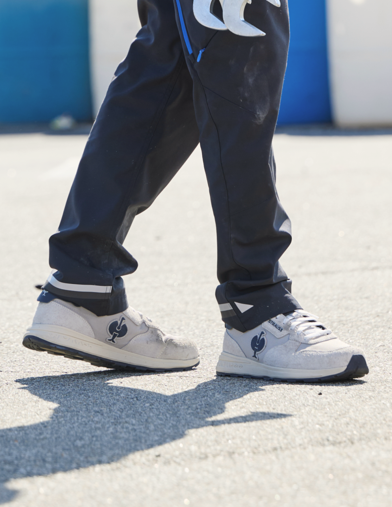 White sneakers with a logo worn on a concrete surface