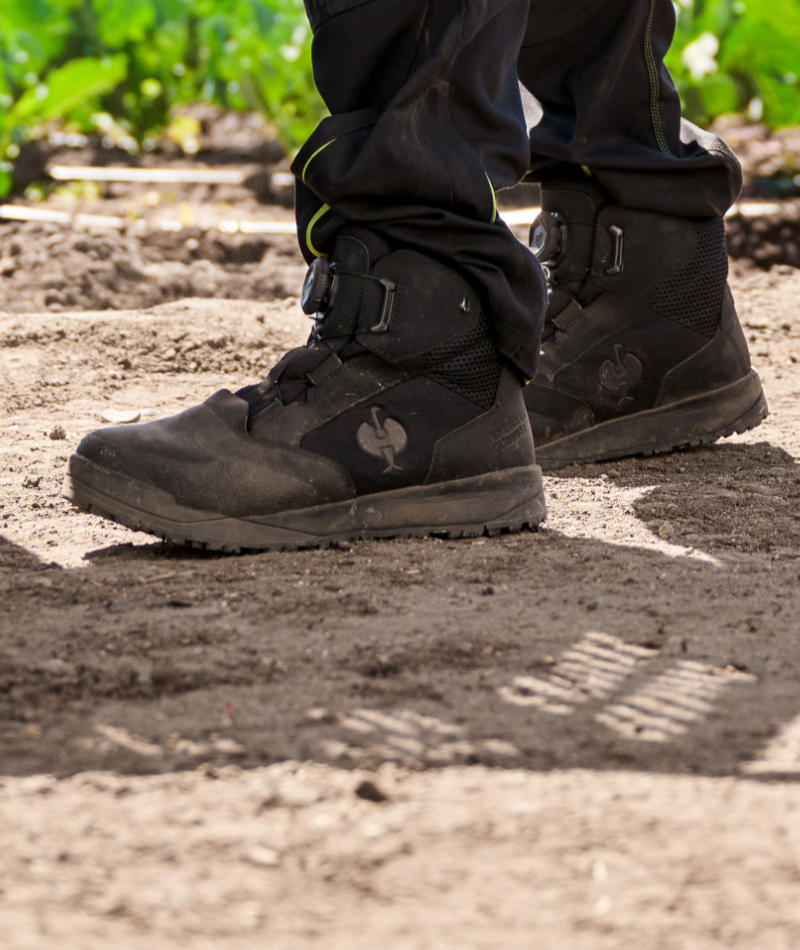 A worker wears STRAUSS Murcia 6-inch Steel Toe Work Boot with cargo work pants on rough jobsite ground.