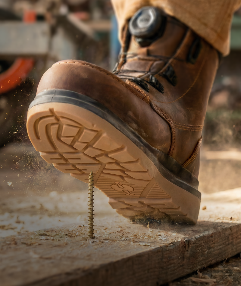 A worker wears STRAUSS Woodside 6-inch Steel Toe Work Boot with cargo work pants on rough jobsite ground.