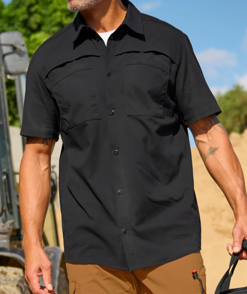 A worker in STRAUSS e.s.taktik Stretch Ripstop Short Sleeve Work Shirt reaches over materials in an outdoor work scene.
