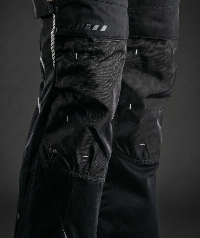 A worker in STRAUSS e.s.motion 2020 Cargo Work Pants kneels while working with tools.