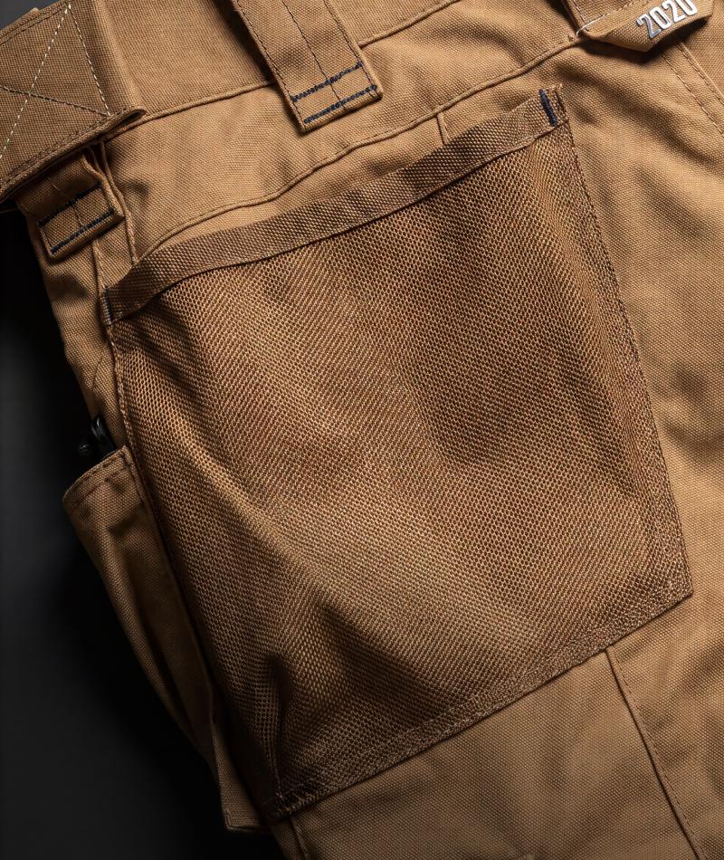 Close-up of a brown canvas utility pocket on a pair of matching brown pants, showing the fabric texture and stitching details.