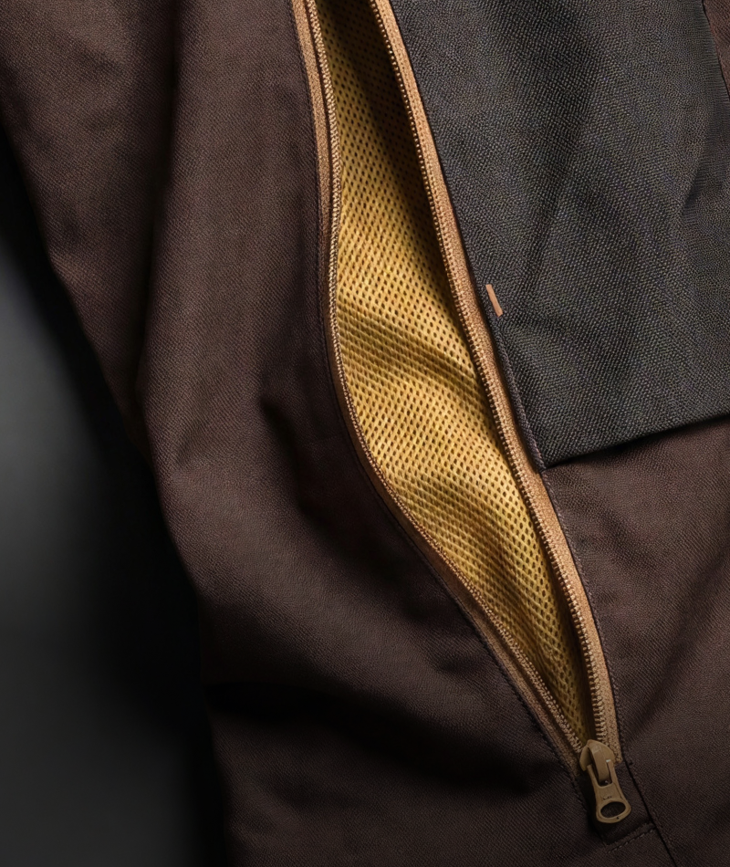 Close-up detail of a dark brown jacket with a tan zipper opening to reveal a mustard yellow mesh lining.