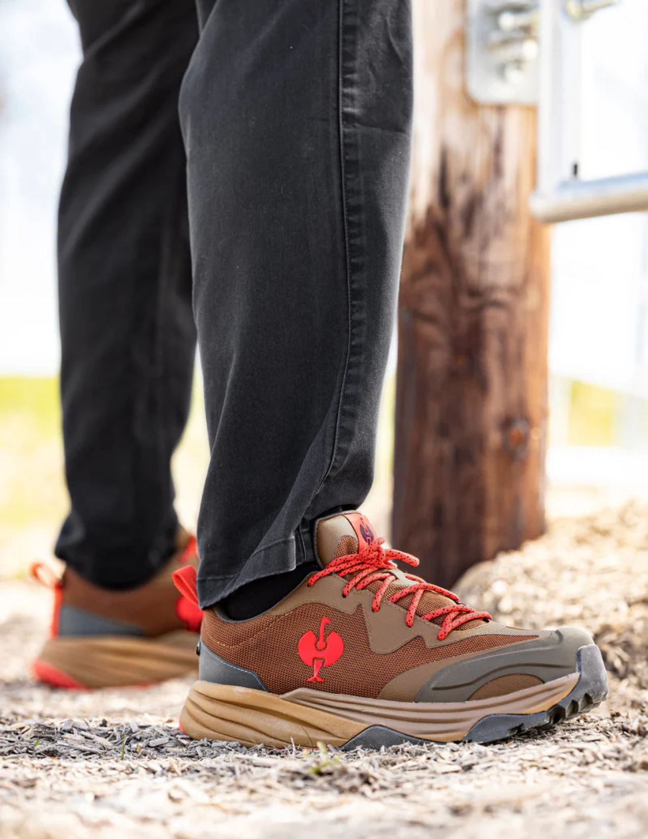 Brown shoes with red accents worn by a person on a natural outdoor setting