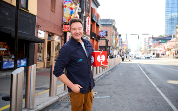 An image of CEO Henning Strauss standing on a road in Nashville, holding a red Strauss cube in his hand.