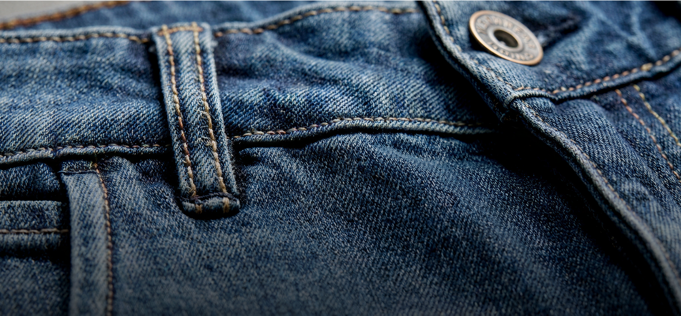Close-up of blue denim fabric with a button and stitching detail