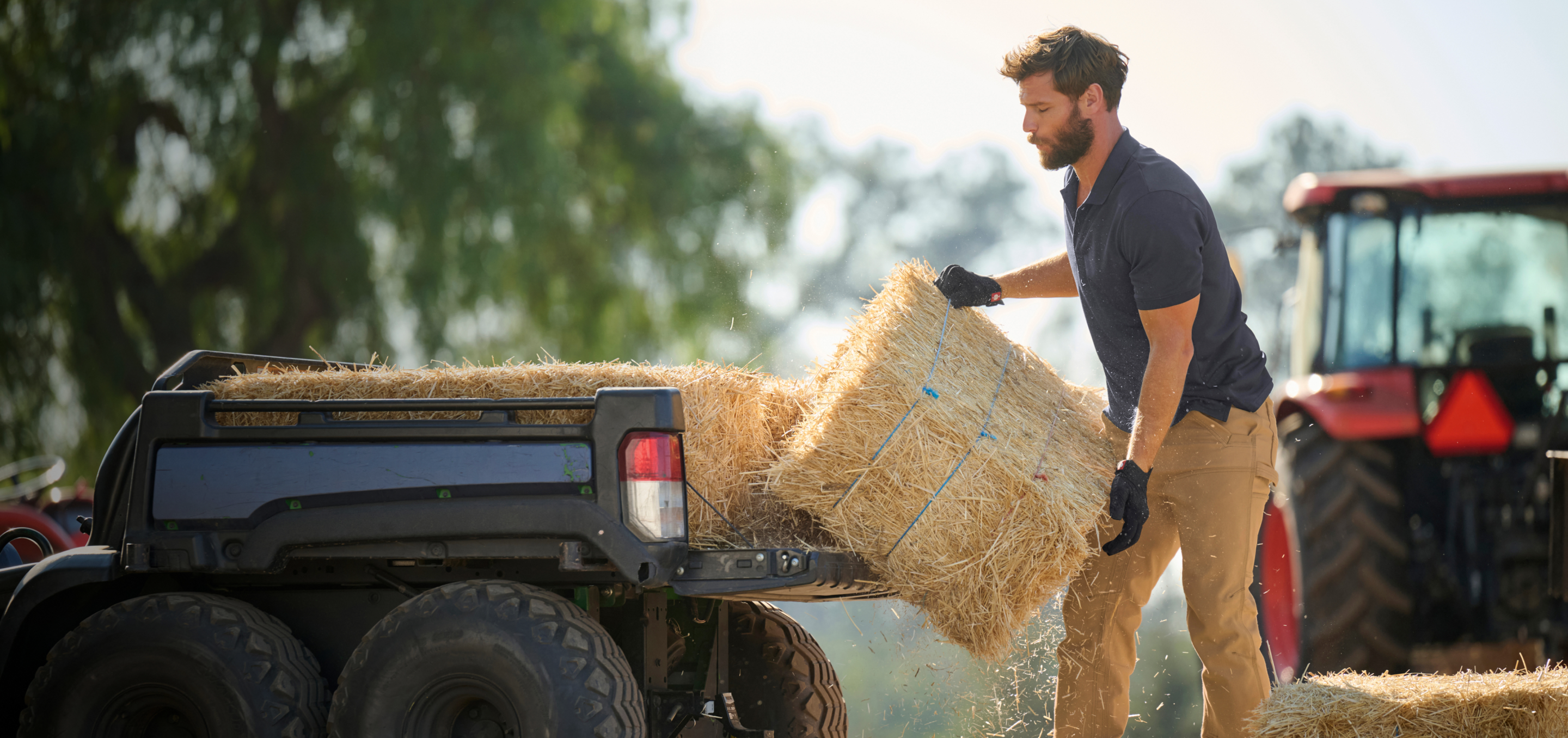 A man lifting a bale of hay onto the bed of a vehicle