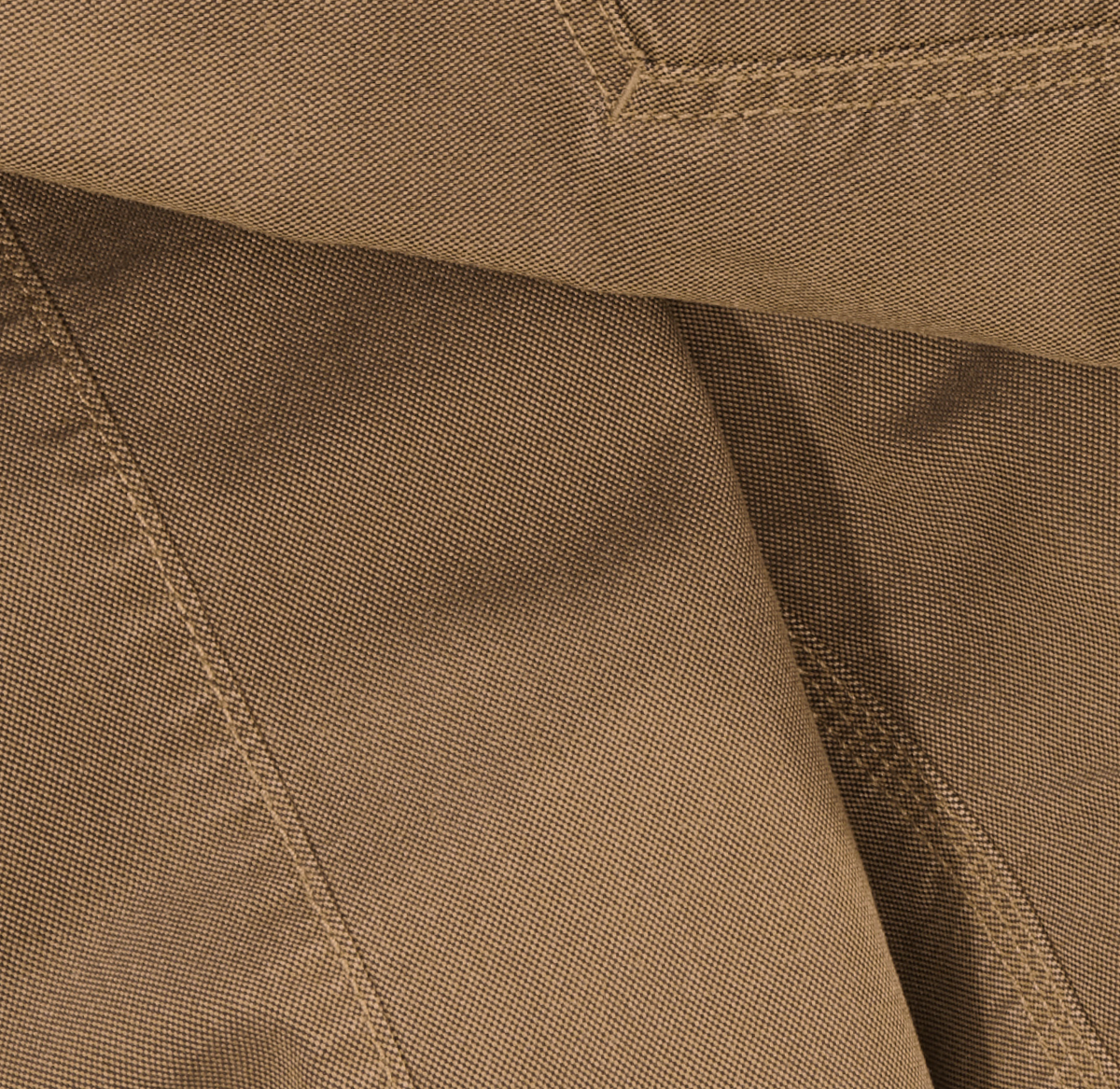 Close-up of light brown fabric with visible stitching and seams, possibly part of a pocket or garment detail. The texture of the textile is clearly shown, highlighting the weave pattern.