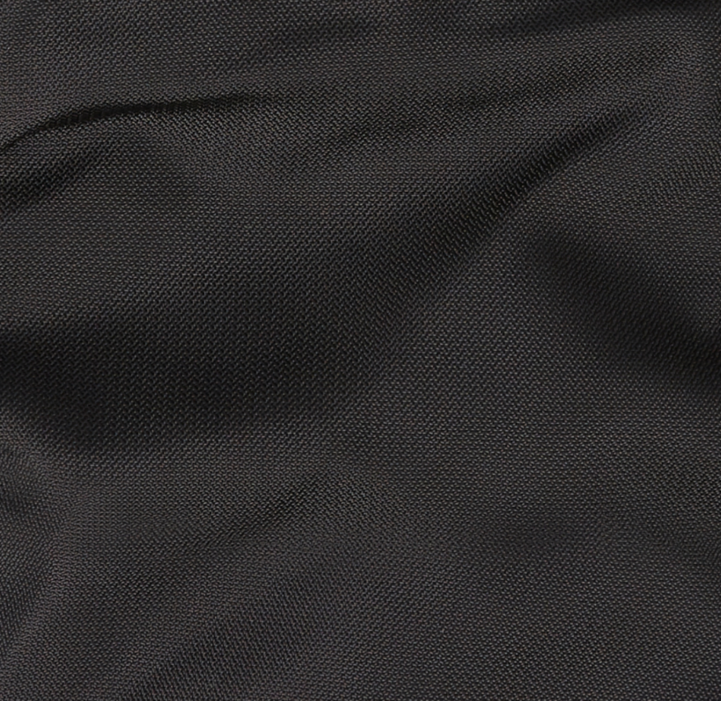 A close-up of dark, textured fabric with visible woven patterns and slight folds, creating a subtle play of light and shadow across the surface.