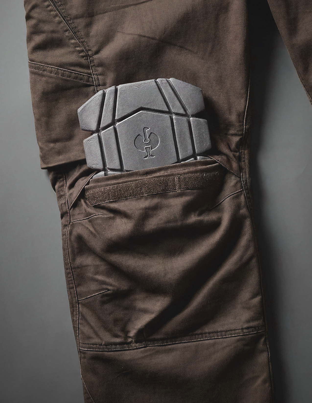A knee pad slit into the knee pocket of a brown cargo work pants