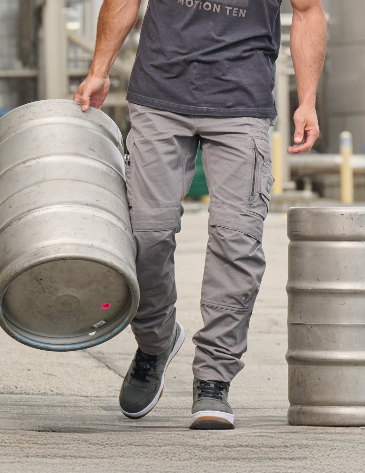 Person carrying a keg wearing gray cargo pants and a dark shirt