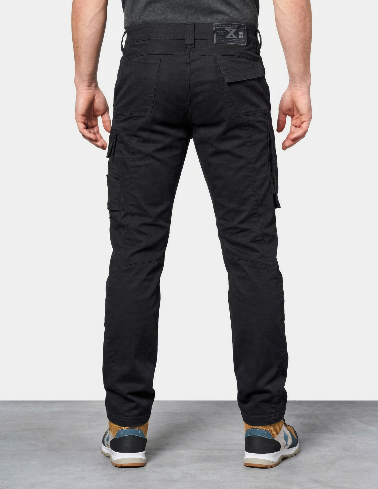 Person wearing black cargo pants on a plain background
