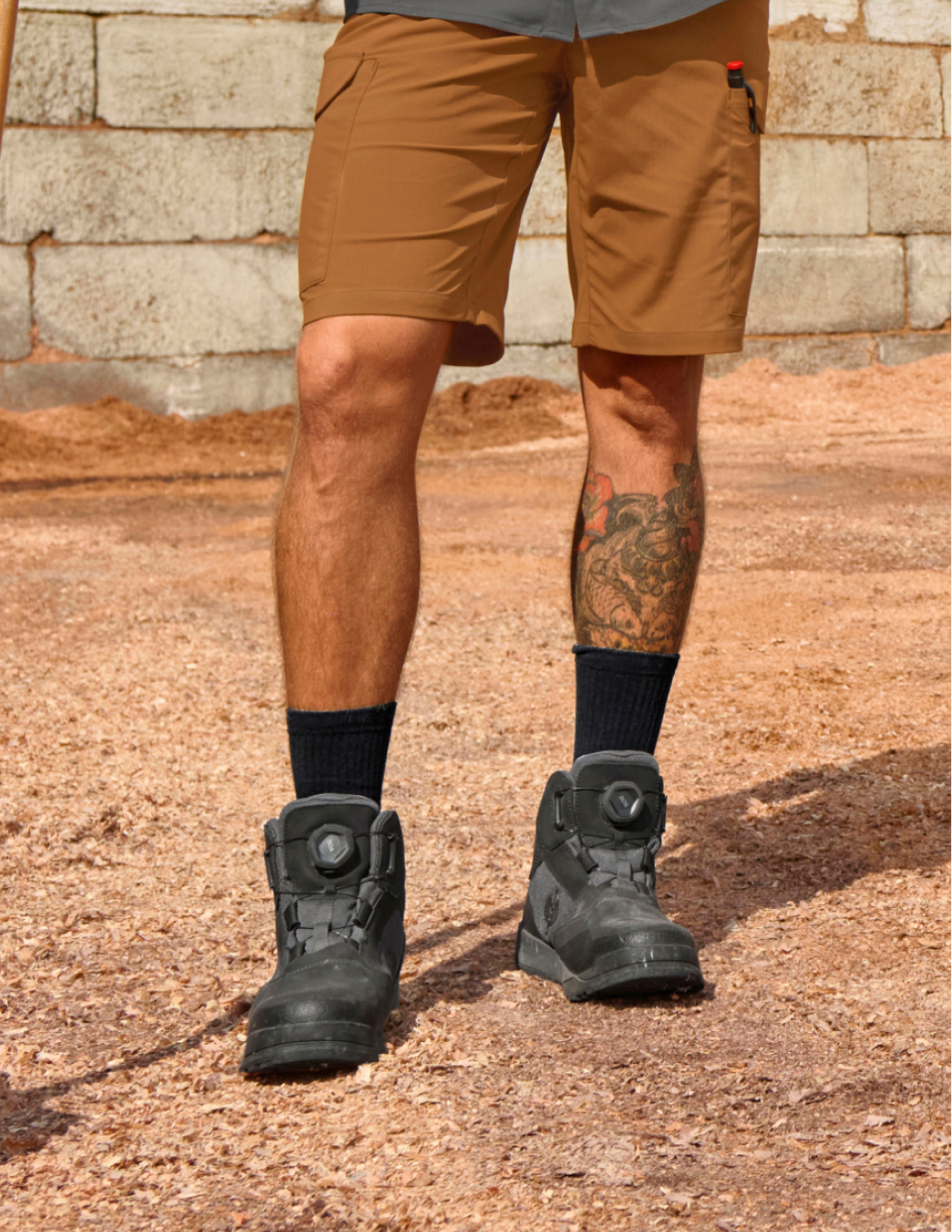 Person wearing the STRAUSS Murcia Mid Steel Toe Work Boots in carbon grey and brown shorts standing on a stone surface