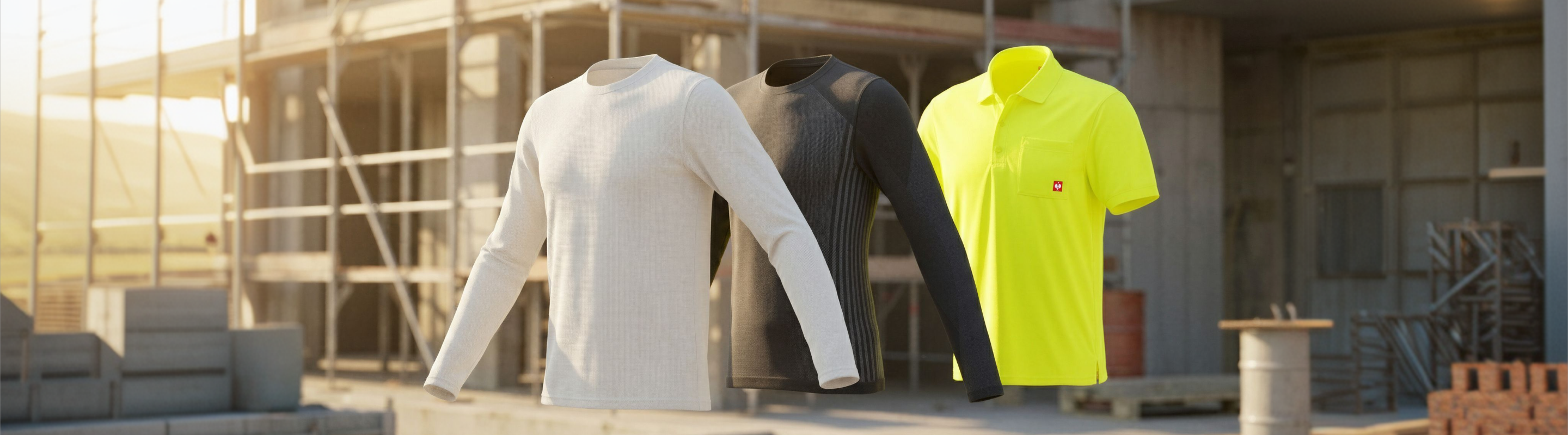 Three shirts—one beige long-sleeve, one black long-sleeve, and one bright yellow short-sleeve polo—are displayed in front of a construction site with scaffolding and building materials in the background.